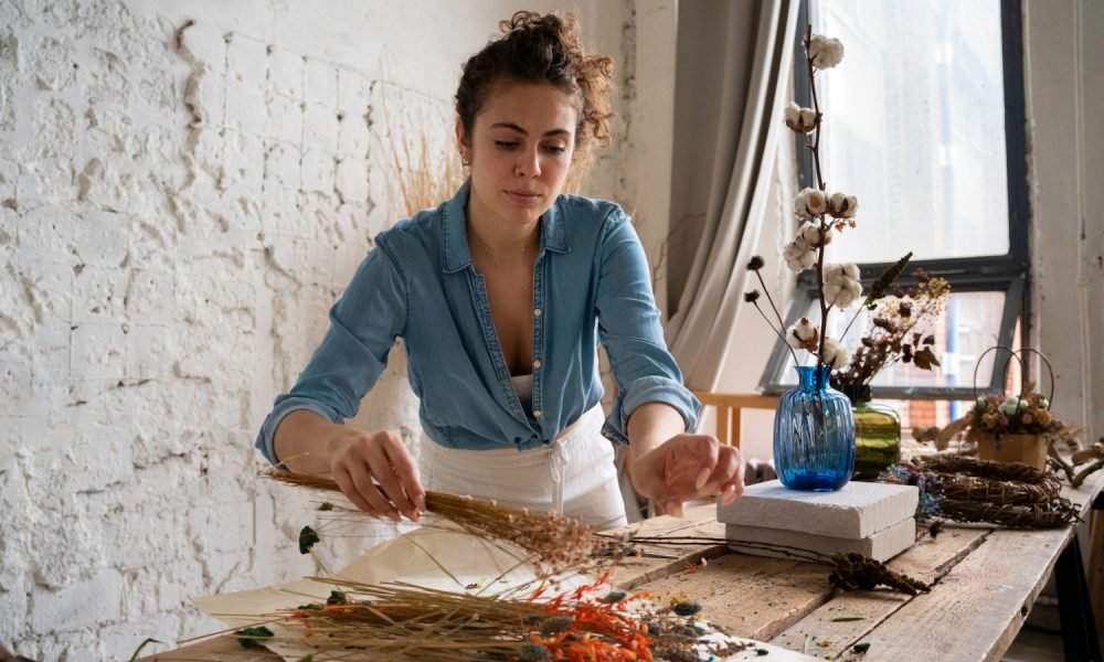 Artesã a trabalhar com materiais numa banca criativa.