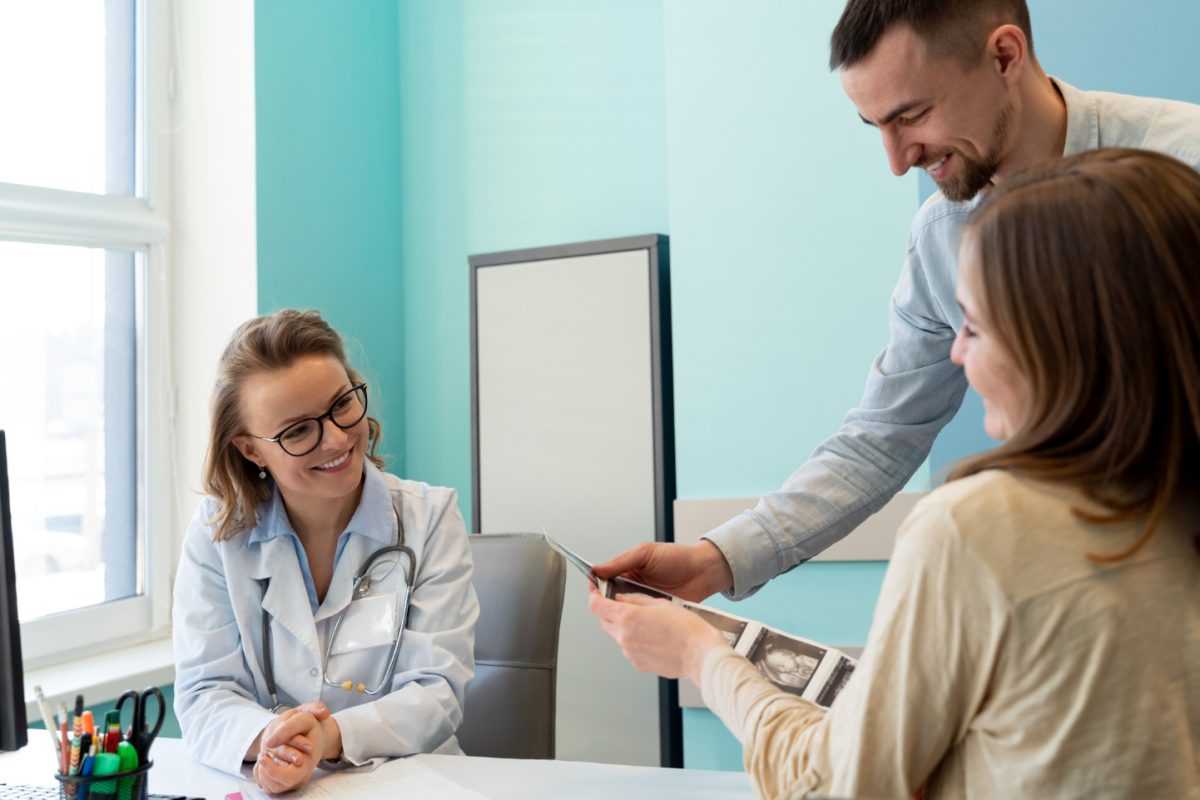 Médica a atender paciente num consultório.