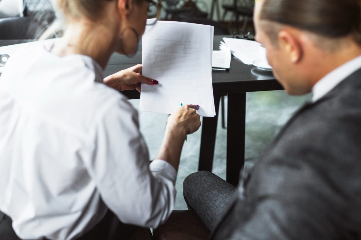 Advogado a explicar cláusulas de um contrato a um cliente.
